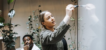 Woman writing on a whiteboard during a planning meeting